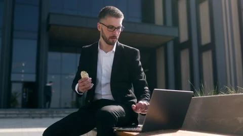 Professional Man in Suit Having Lunch and Typing on Laptop in Urban Setting Vídeo Stock 330795309