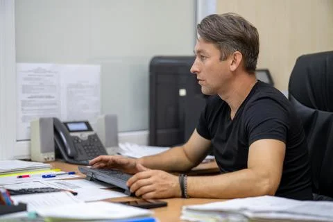 Professional man typing on keyboard while looking at a computer monitor. Of.. Stock Photos