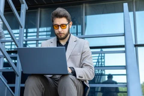 Professional man using laptop while sitting outdoors in the city Stock Photos