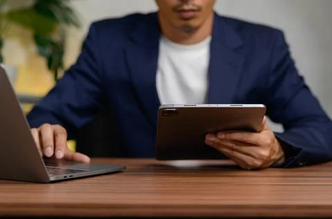 Professional Man Using Tablet and Laptop in Modern Workspace Stock Photos