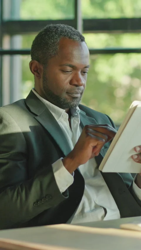 A professional man is utilizing a tablet while seated in a contemporary 動画素材 314362621