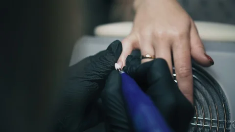 Professional manicure master in black gloves doing manicure using nail tools in Stock Footage 93985734