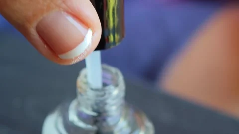 Professional manicurist gently uncapping clear polish bottle, displaying Stock-Footage 315361230