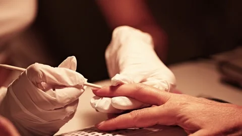 Professional manicurist pushing back cuticles during manicure treatment 動画素材 342313991