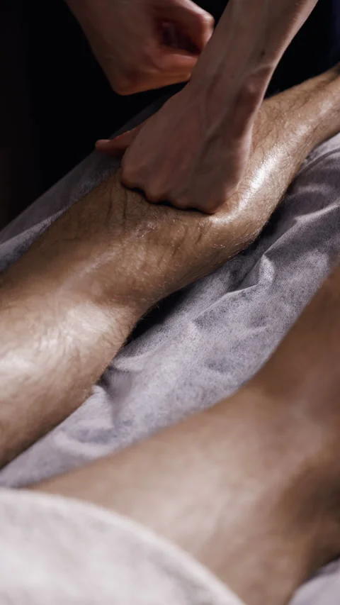 Professional massage therapist performing deep tissue leg massage with targeted Video stock 338007607