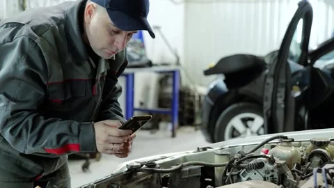 Professional mechanic capturing car engine details using smartphone while Stock Footage 304711321
