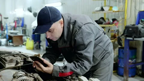 Professional mechanic checking diagnostic data on digital tablet near vehicle Vídeos de archivo 328020938