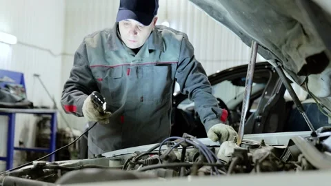 Professional mechanic checking vehicle engine compartment, using flashlight for Stock Footage 341288995