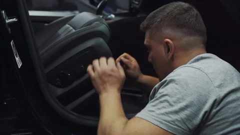 Professional mechanic fixing seat inside dark car Stock Footage 141660629