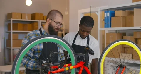 Professional mechanic teach apprentice how to repair bike in workshop Stock Footage 160480118