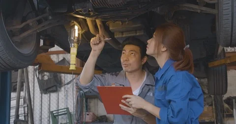 Professional mechanic team working under lifted car at auto repair shop. Video stock 100236177