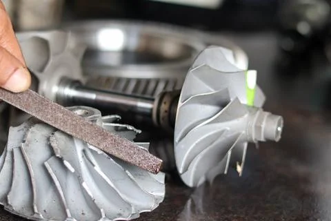 Professional mechanic using abrasive sanding belt to smooth metal turbochar.. Stock Photos