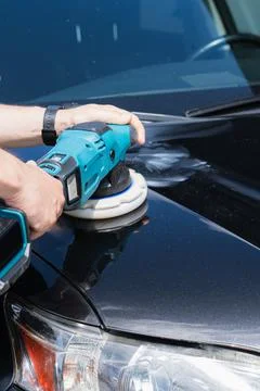 Professional mechanic using a teal handheld electric orbital polisher to bu.. Stockfoto's