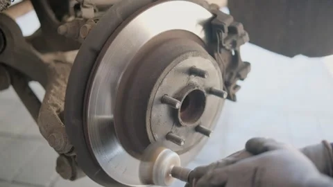 Professional mechanic wearing gloves using a rotating brush on a power drill to Stock Footage 339273827