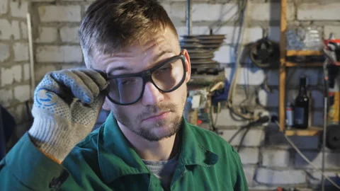 Professional mechanic in workwear taking off protective glasses and wiping sweat Video stock 246543580