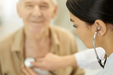 Professional medic using stethoscope to examine her elderly patient Stock Photos