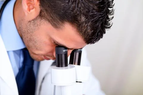 Professional medical man using a microscope Stock Photos