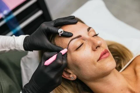 Professional microblading procedure on woman's eyebrows 库存照片
