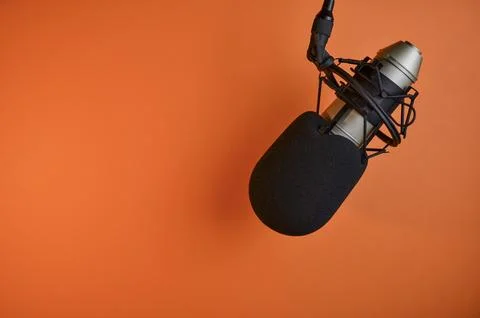 Professional microphone hanging on an orange background ready for recording.. Stock Photos