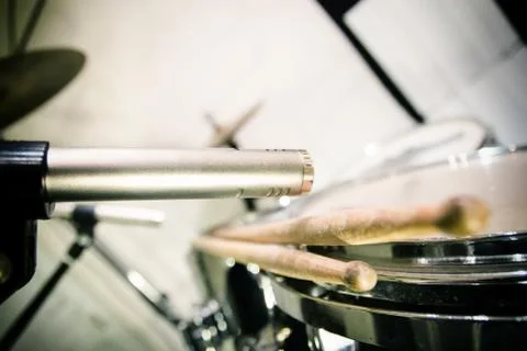 Professional microphone placed close to drums with sticks Stock Photos