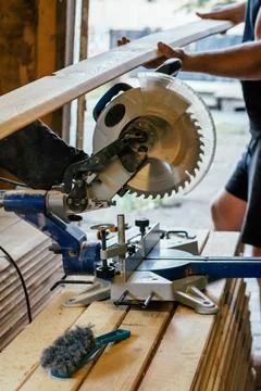 Professional miter saw standing on stack of boards with trim planks for house Foto stock