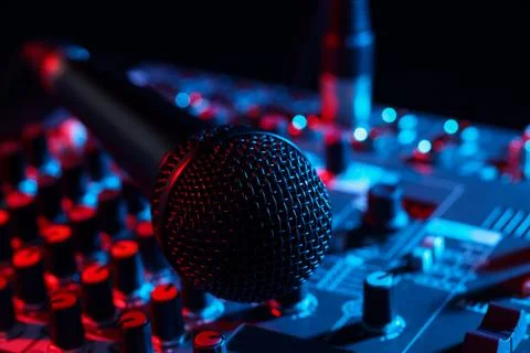 Professional mixing console with microphone on black background in neon lig.. Stock Photos