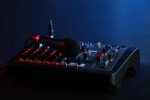 Professional mixing console with microphone on table against dark blue back.. Stock Photos