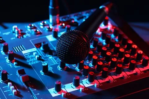 Professional mixing console with microphone on table in neon lights, closeup Stock Photos