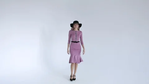 The professional model comes forward in a black hat in purple dress and posing  Stock Footage 106284050