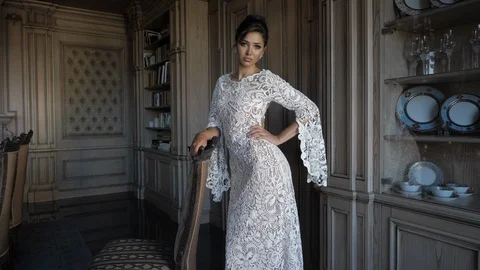 Professional model in long white lacy dress poses near chair Stock Footage 125056123