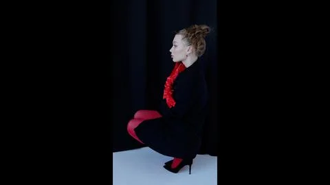 Professional model posing in studio, wearing red tights, gloves, black dress Stock Photos