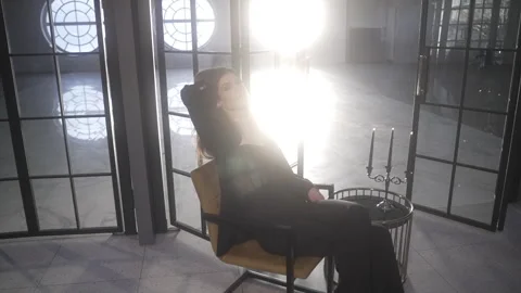 A professional model sits and moves against the backdrop of huge round windows. Vidéo 261558668