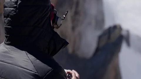 Professional mountaineer piloting drone over rugged mountain peaks, capturing Stock Footage 297614112