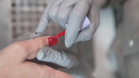 Professional nail technician applies bright red gel polish to a clients Stock Footage 311875053