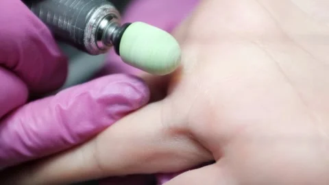 Professional nail technician using electric manicure drill to remove callus from Stock Footage 326252254
