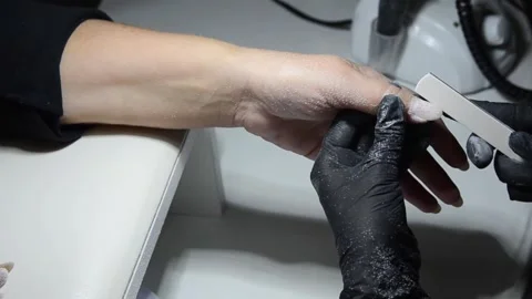 Professional nail technician using a manual nail file to remove old gel polish Stock Footage 340815905