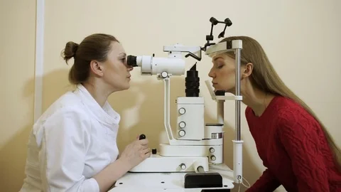 Professional oculist examining and treating eyes of an young pretty woman. HD Video stock 74996337