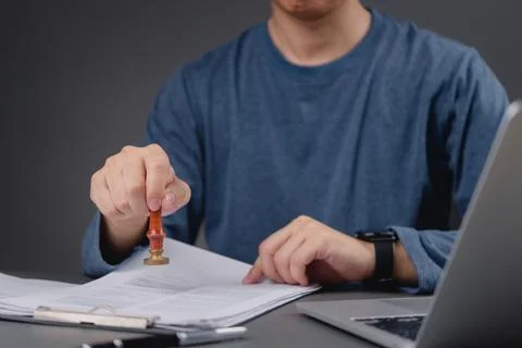 Professional office worker using a stamp on paperwork, demonstrating the ad.. Stock Photos