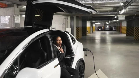 Professional operating computer in EV on charge in garage Video stock 250782294
