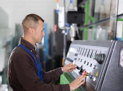 Professional operator working at machinery control panel in glass plant Stock Photos