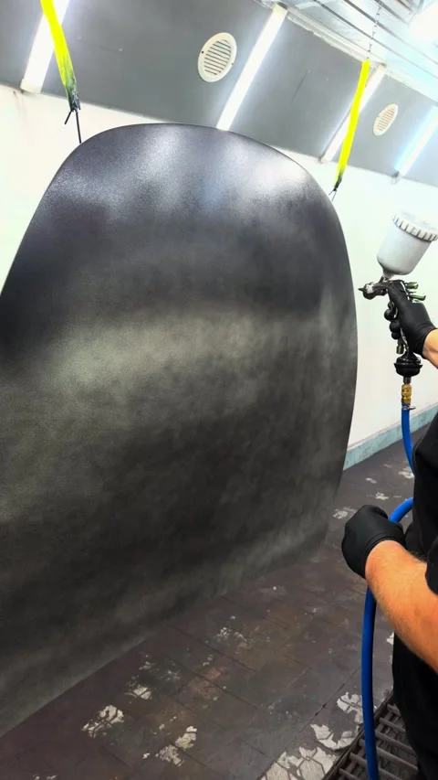 Professional painter applying dark grey paint with spray gun in a booth Stock Footage 341134755