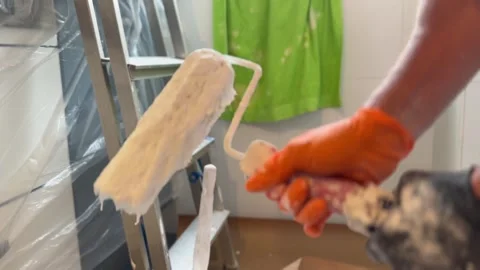 Professional painter dipping a roller into a white paint bucket Vidéo 341363139