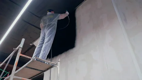 Professional painter man paints wall in black with sprayer Stock Footage 146678886