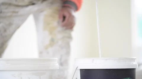 Professional painter mixes paint in large bucket Stock Footage