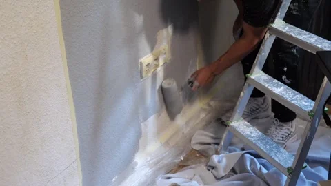 Professional Painter Rolling Grey Paint on Lower Wall Around Power Outlets .. Stockbeeldmateriaal 347724777