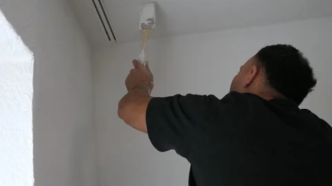 Professional Painter Using Brush to Paint Ceiling Corner White in Room Reno.. Stockbeeldmateriaal 347724523
