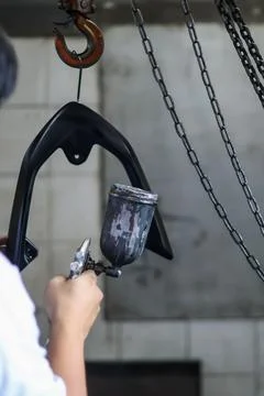 A professional painter using a spray gun to apply a sleek black matte Stock Photos