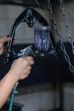 A professional painter using a spray gun to apply a sleek black matte Stock Photos