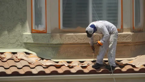 Professional painter using a sprayer to paint the stucco on a home Видео 133613247