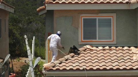 Professional painter using a sprayer to paint the stucco on a home Stock Footage 133613256